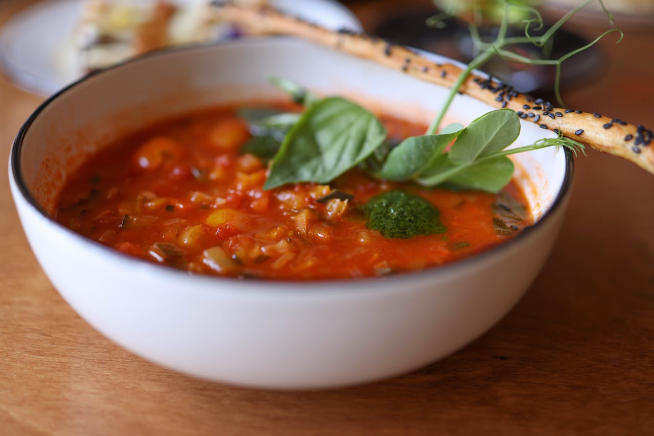 A warm bowl of homemade tomato soup garnished with fresh herbs